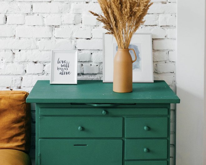 A drawer with two painting and a flower vase on it